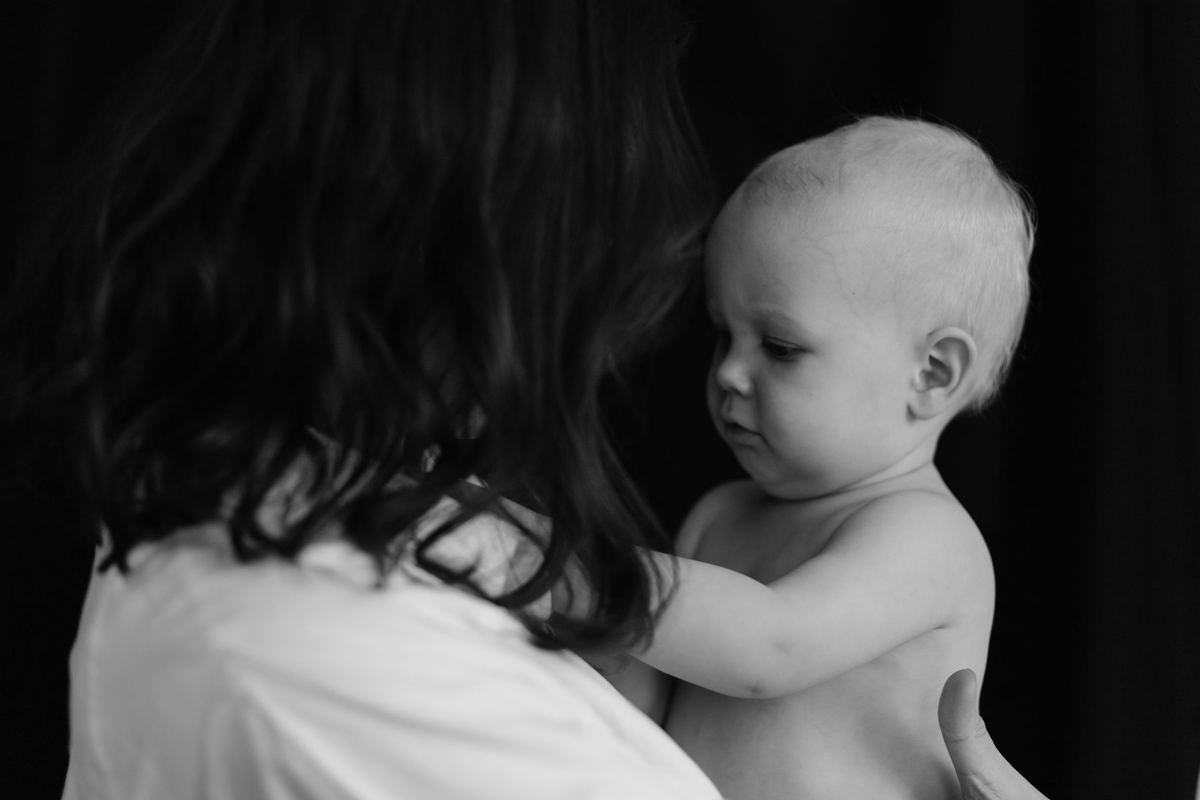 Mãe de costas segurando o bebê no colo, foto em preto e branco