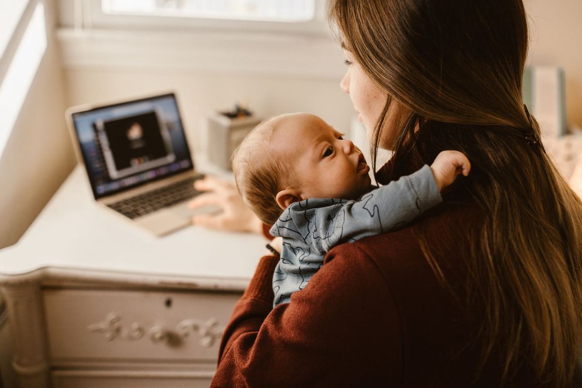 Mãe segurando o bebê enquanto trabalha em casa
